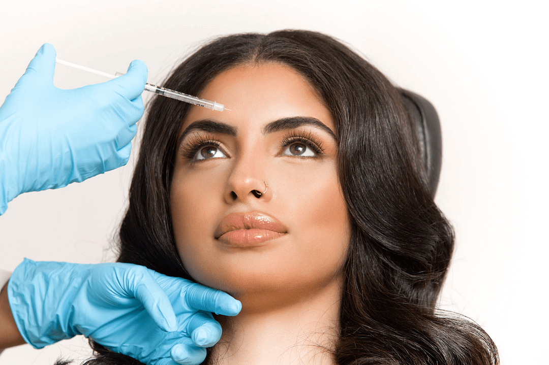 Close up shot of a model's face getting Botox injections to her forehead by a gloved provider